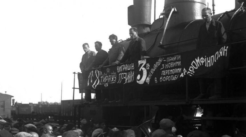 Black and white photo of a train with grain and people speaking on it