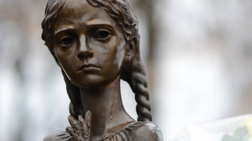 Скульптура дівчинки. Вона тримає в руках 5 колосків і боязко озирається довкола. 