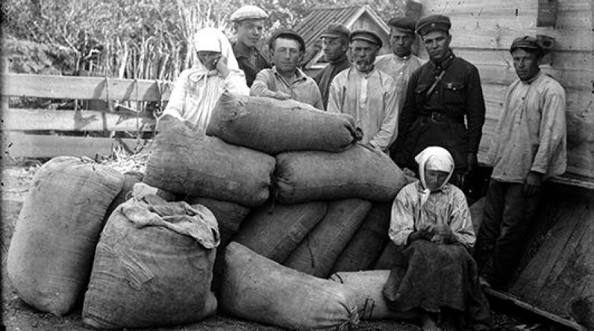 Чорно- біле фото селян, що стоять біля мішків з харчами